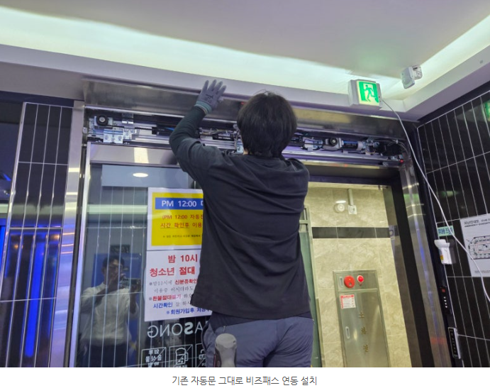 설치 기술자가 자동문 상단의 제어 장치를 연동하는 모습